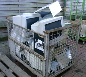 Foto: Eine Gitterbox mit defekten Computermonitoren und Blechen